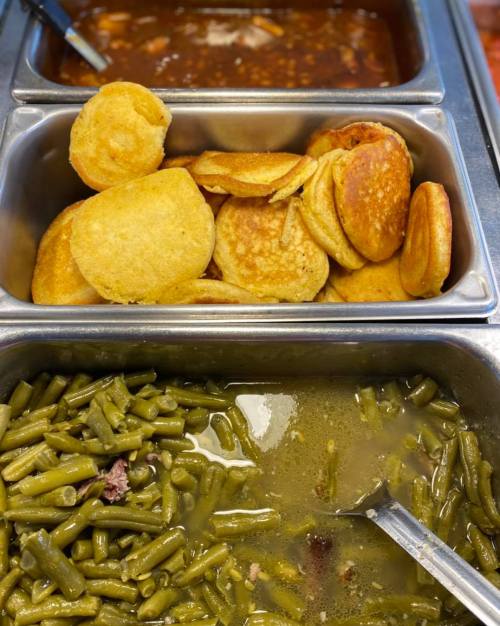 A metal serving tray with cornbread, green beans, and a brown bean dish.