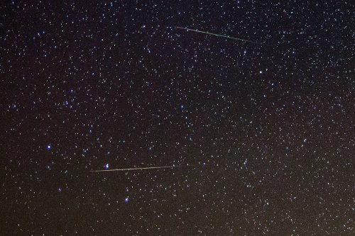 A starry night sky with several bright meteors streaking across the dark background filled with stars.