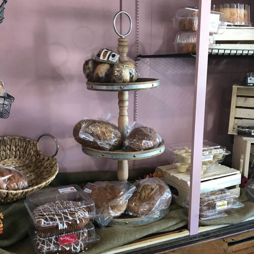 A tiered display of assorted baked goods, including muffins and loaves, in a cozy bakery setting.