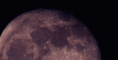 Close-up view of the moon's surface, showcasing craters and textures against a dark sky.