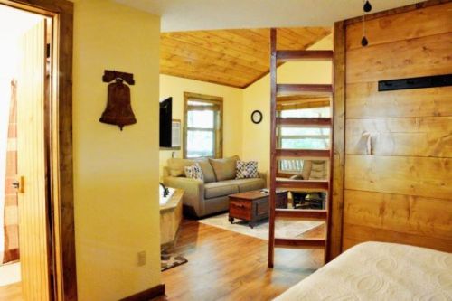 Cozy interior of a cabin featuring a living area with a sofa, wooden accents, and a partitioned bedroom space.