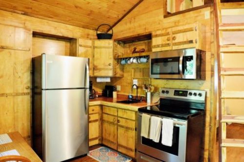 Cozy wooden kitchen with stainless steel appliances, including a fridge and stove, and a staircase leading to an upper level.