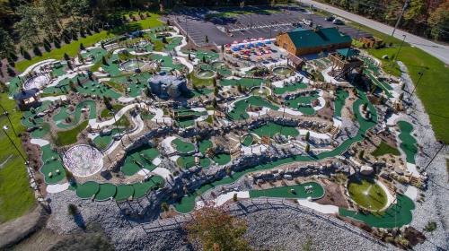 Aerial view of a mini-golf course with winding paths, water features, and a parking lot nearby.