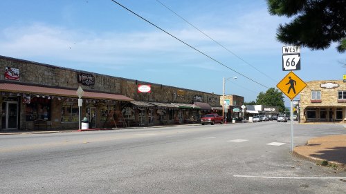 A view of a historic street with shops, a Route 66 sign, and clear blue skies.