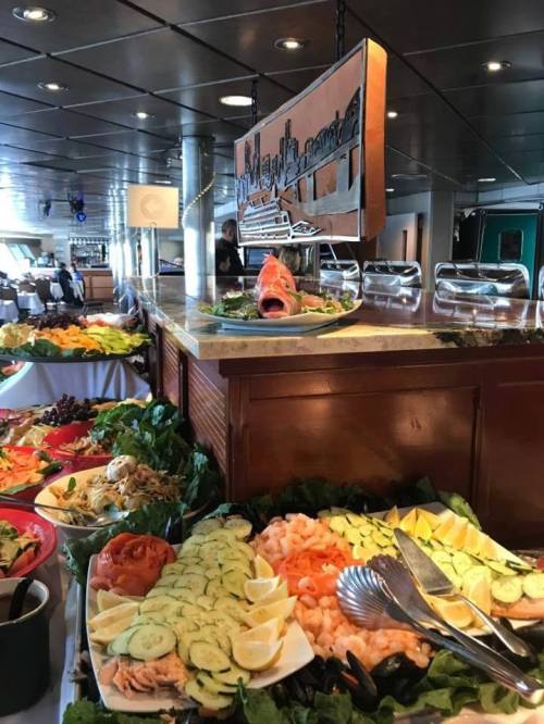A buffet table with a variety of dishes, including seafood, salads, and garnishes, set in a dining area.