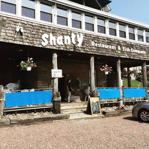 Exterior of Shanty Restaurant & Fish Company, featuring wooden architecture, hanging flower baskets, and a welcoming entrance.