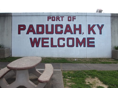 Mural on a wall reading "Port of Paducah, KY Welcome" with a picnic table in front.