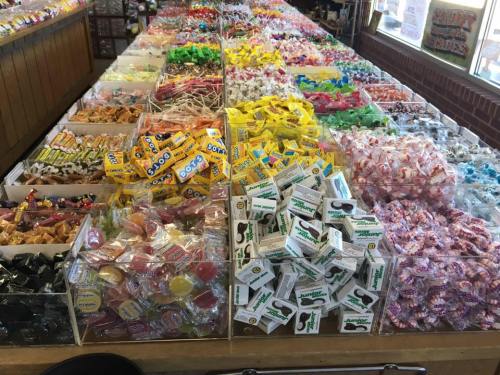 A colorful display of various candies in bins, including lollipops, gummies, and wrapped sweets.