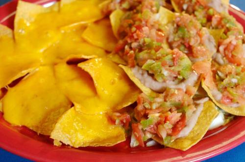A plate of nachos topped with salsa and melted cheese, served with crispy tortilla chips.