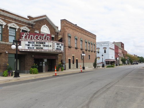 A quiet street scene featuring the Lincoln theater marquee and historic brick buildings under a cloudy sky.