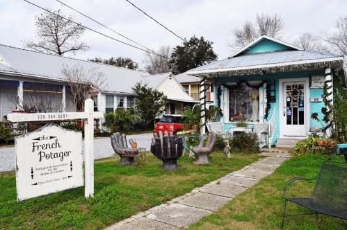 Quaint shopfront of "The French Potager" with colorful decor, outdoor seating, and a welcoming garden.