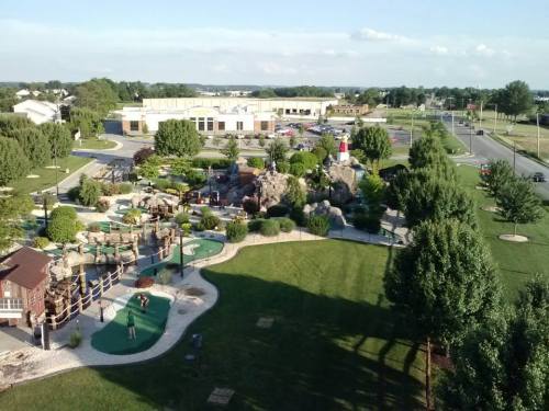 Aerial view of a mini-golf course with lush greenery, rock formations, and players enjoying the game.