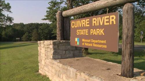 Sign for Cuivre River State Park, featuring natural stone and wooden posts, surrounded by green grass and trees.