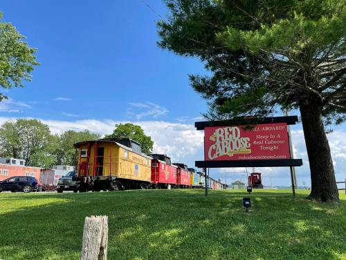 A colorful train caboose next to a sign advertising a motel experience in a caboose, set against a blue sky.