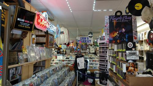 A vibrant record store interior filled with vinyl records, neon signs, and music memorabilia.
