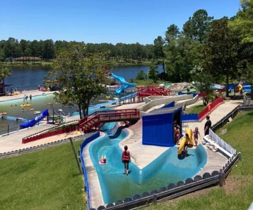 A vibrant water park scene with slides, a lazy river, and families enjoying the sunny day by a lake.