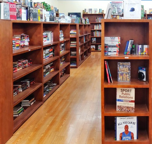 A cozy bookstore interior with wooden shelves filled with various books and a warm wooden floor.