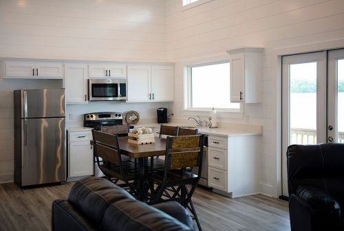 Modern kitchen with stainless steel appliances, white cabinets, and a dining table, overlooking a scenic view.