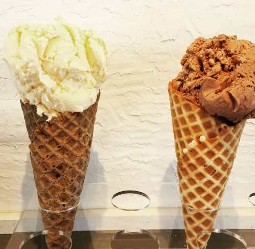 Two ice cream cones: one with creamy vanilla and the other with rich chocolate, displayed against a textured background.