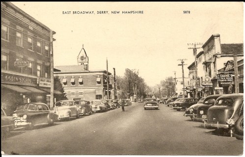 Black and white photo of East Broadway in Derry, New Hampshire, featuring vintage cars and storefronts.