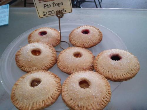 A plate of pie tops with various fruit fillings, each topped with sugar, displayed for sale.