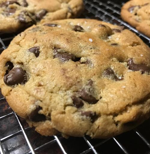 Freshly baked chocolate chip cookies cooling on a wire rack, with a golden-brown color and chocolate chunks visible.