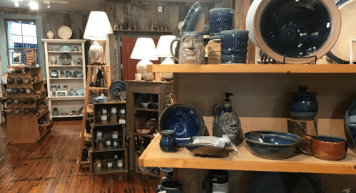 A cozy shop interior displaying various blue pottery items on wooden shelves and tables.