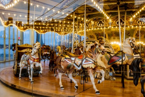 A beautifully lit carousel with intricately painted horses, set against a backdrop of twinkling lights.