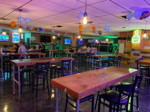 A brightly lit restaurant interior with wooden tables, chairs, and colorful balloons, featuring a few patrons.