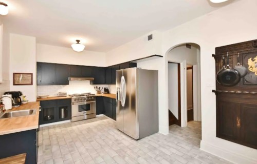 Modern kitchen with dark cabinets, stainless steel appliances, and a wooden countertop, featuring a spacious layout.