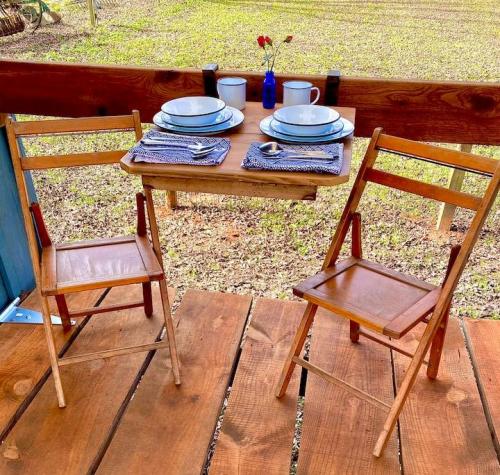 A cozy outdoor dining setup with two wooden chairs, a small table, and plates on a rustic deck.