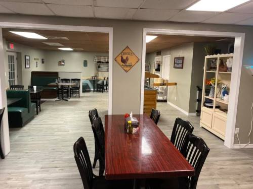 A cozy restaurant interior featuring wooden tables, black chairs, and green booths, with a welcoming atmosphere.