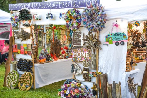 A vibrant craft booth featuring handmade decorations, including flowers, signs, and colorful ornaments.