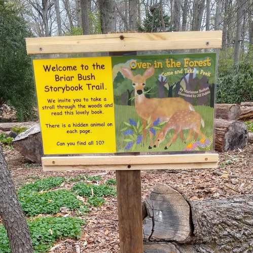 Sign for the Briar Bush Storybook Trail inviting visitors to explore and find hidden animals in the book.