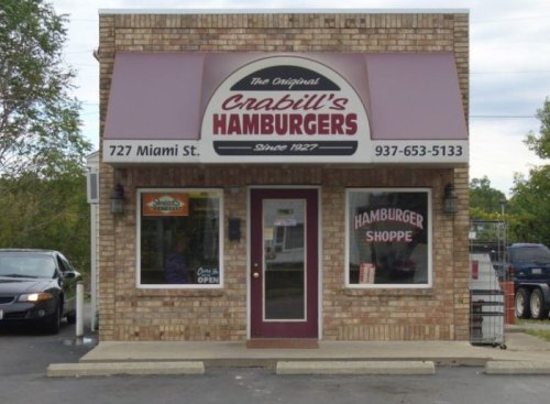 A brick building with a sign reading "Crabill's Hamburgers" and a small window displaying "Hamburger Shoppe."