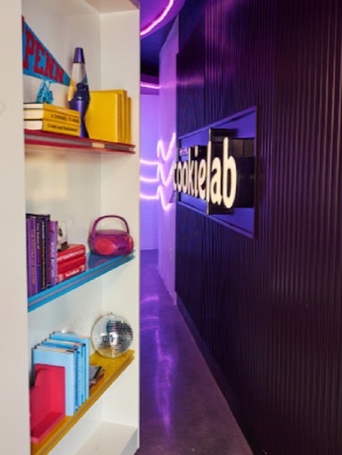 A colorful hallway leading to "cookielab," featuring shelves with books and a disco ball.