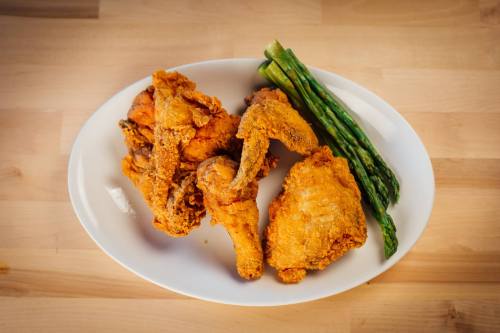 A plate of crispy fried chicken pieces served with fresh asparagus on the side.
