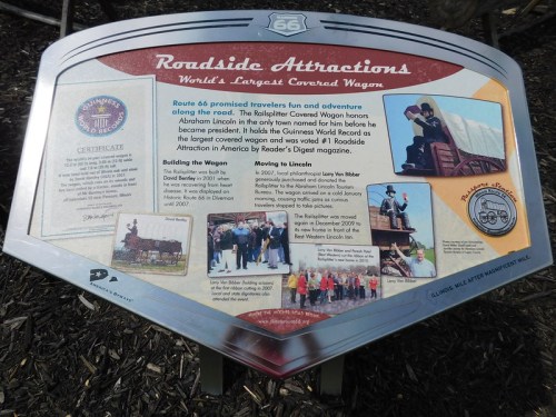 Sign about the World's Largest Covered Wagon on Route 66, detailing its history and significance.