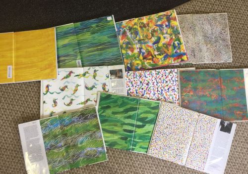 A collection of colorful art prints displayed on a textured surface, featuring various abstract and patterned designs.