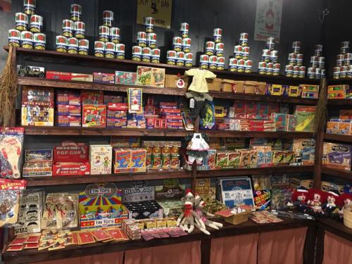 A vintage toy store display featuring colorful boxes, games, and stuffed animals on wooden shelves.