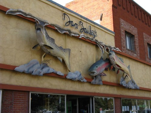 A colorful fish sculpture on a building facade, featuring trout and a flowing water design.