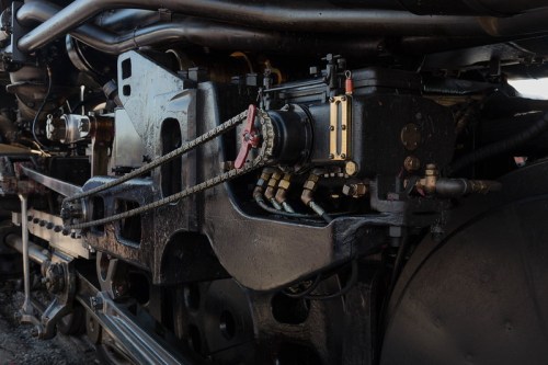 Close-up of a steam locomotive's mechanical components, showcasing intricate metalwork and piping.