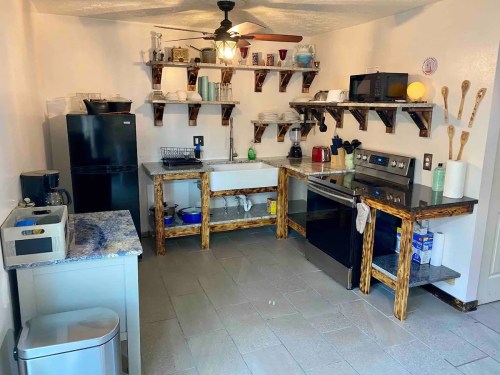 A modern kitchen featuring wooden shelves, stainless steel appliances, and a farmhouse sink with a spacious layout.