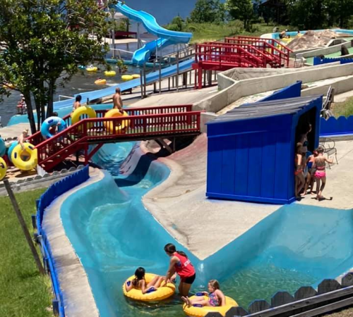 A water park scene with slides, a lazy river, and people enjoying the attractions on inflatable tubes.