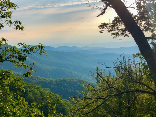 A scenic view of rolling mountains and lush greenery under a soft, cloudy sky.