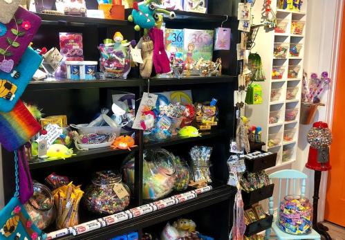 A colorful display of toys, crafts, and candies on shelves in a vibrant store.