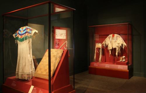 Display of traditional garments and artifacts in a museum setting, featuring intricate designs and textures.