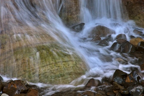 A close-up of a waterfall cascading over smooth rocks, creating a serene and tranquil scene.