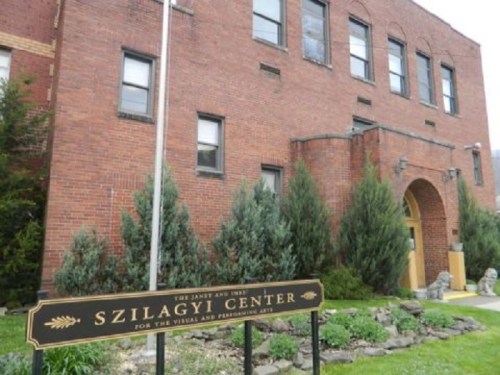 Exterior view of the Szilagyi Center, a brick building with greenery and a sign for the Visual and Performing Arts.
