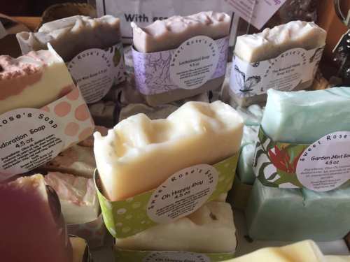 A variety of colorful handmade soaps displayed with labels, showcasing different scents and designs.